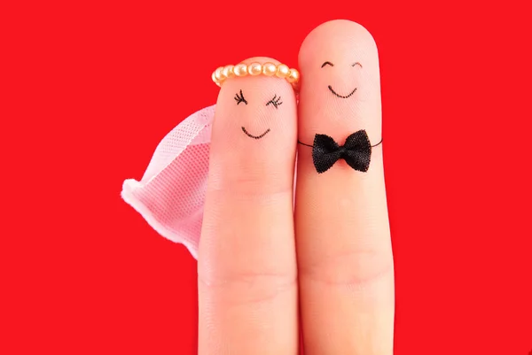 Recém-casados abraço pintado em dedos isolados em fundo vermelho — Fotografia de Stock