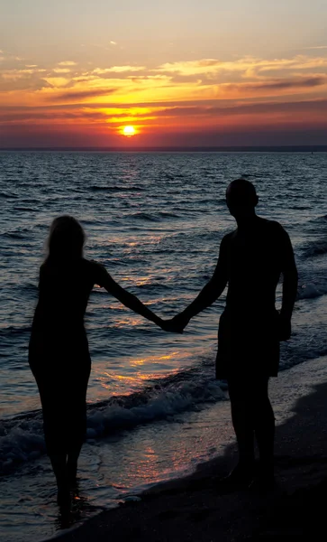 Couple silhouette on beach against sunset — Stock Photo, Image