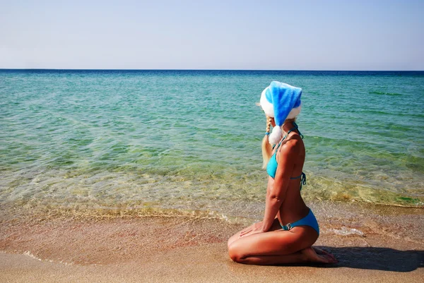 Mulher bonita em azul chapéu de Papai Noel na costa do mar areia — Fotografia de Stock