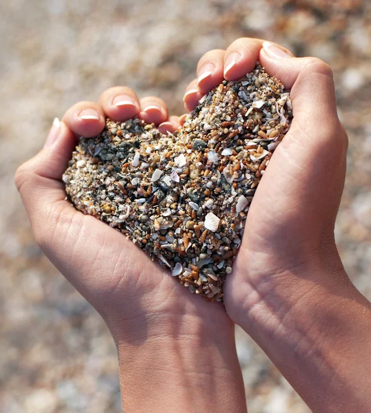 Manos sosteniendo una arena en forma de corazón — Foto de Stock