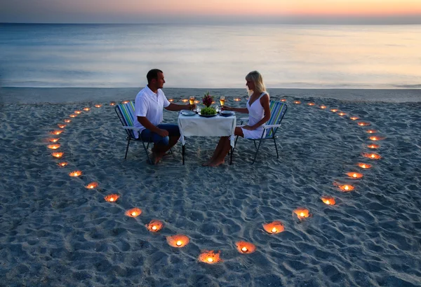 Un jeune couple d'amoureux partage un dîner romantique avec des bougies coeur — Photo