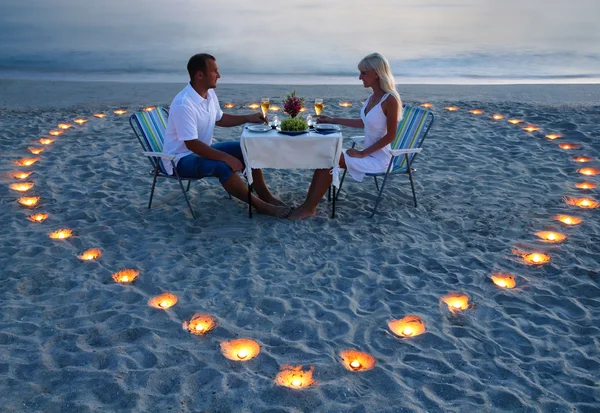 Um jovem casal de amantes compartilha um jantar romântico com o coração de velas — Fotografia de Stock