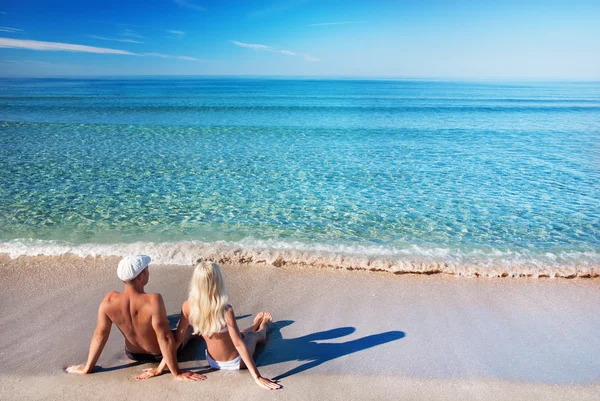 Verliefde paar zittend op de zee zand strand en kijken naar de blauwe — Stockfoto