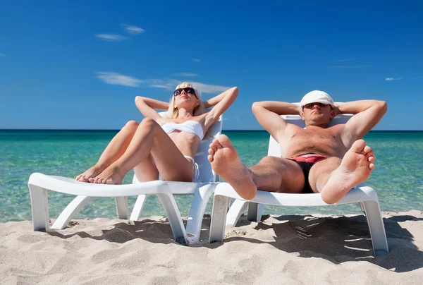 Giovani coppie prendere il sole sul lettino sulla spiaggia sul mare — Foto Stock