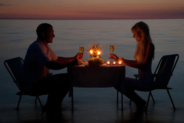 Genç bir çift sahilde mum ile romantik bir akşam yemeği paylaşmak — Stok fotoğraf