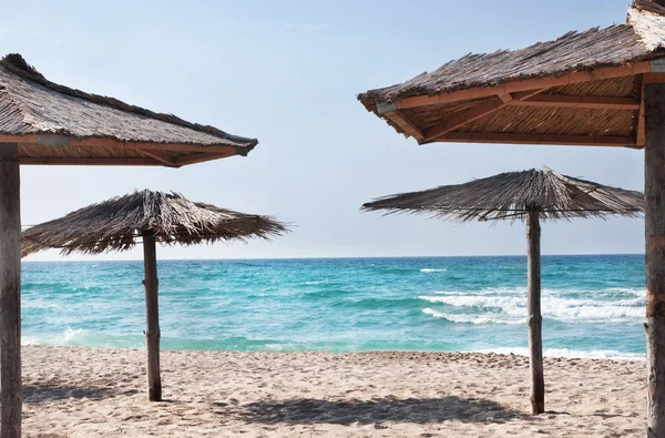 Rena tropiska stranden med halm stranden paraplyer — Stockfoto