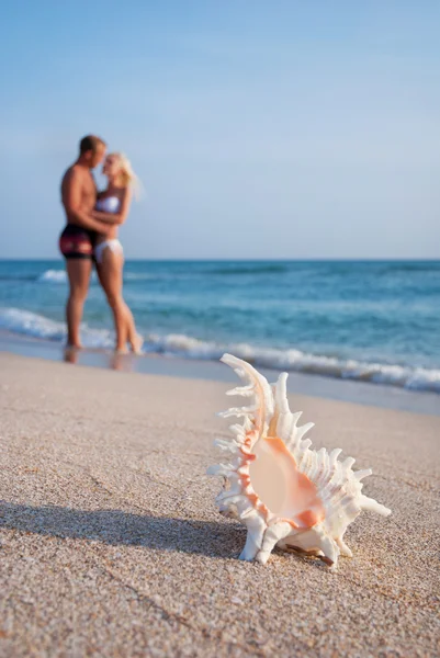 Loving couple hug one another on the sea sand beach against big — Stock Photo, Image