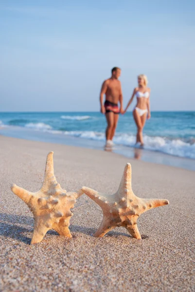 Pareja amorosa caminando en la playa de arena del mar contra estrellas de mar un —  Fotos de Stock