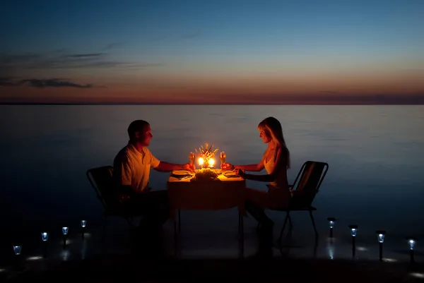 Um jovem casal compartilha um jantar romântico com velas na praia Fotos De Bancos De Imagens