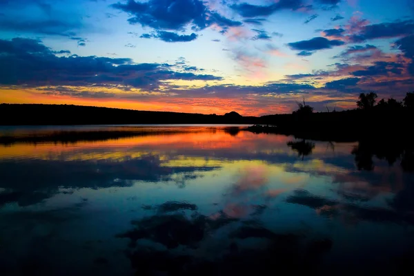 Sista solstrålar ovanför sjön i molnig kväll — Stockfoto