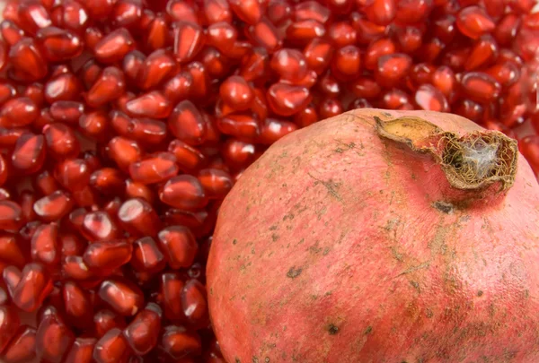 Pomegranate fruit on pomegranate seeds background — Stock Photo, Image