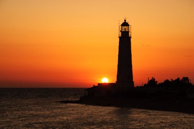 fener kulesi üstünde parlak deniz günbatımı panorama