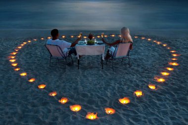A young couple share a romantic dinner on the beach clipart