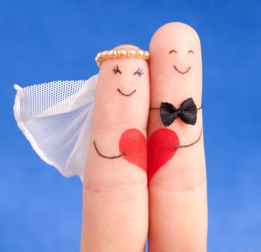 Wedding concept - newlyweds painted at fingers against blue sky clipart