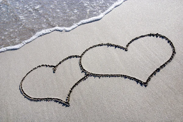 Heart outline on beach sand with wave — Stock Photo, Image