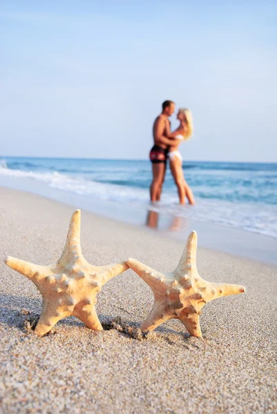 Pareja abrazo en mar arena playa contra estrellas de mar —  Fotos de Stock