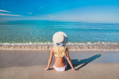 Cute blonde woman in white bikini on sea sand beach clipart