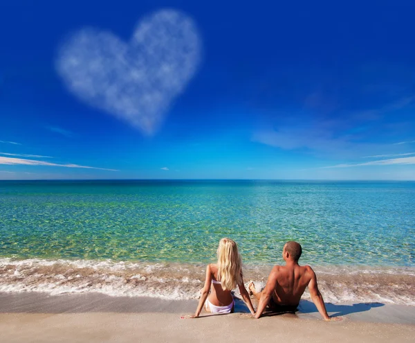 Genç bir çift deniz üzerinde oturan plaj kum ve gökyüzüne bak — Stok fotoğraf