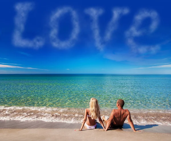 Ungt par sitter på havet sand stranden och titta på himlen — Stockfoto