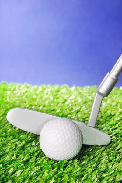 Golf ball and club on green field grass against blue sky — Stock Photo, Image