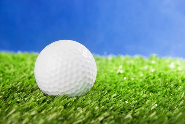 Golf ball on green field grass against blue sky — Stock Photo, Image