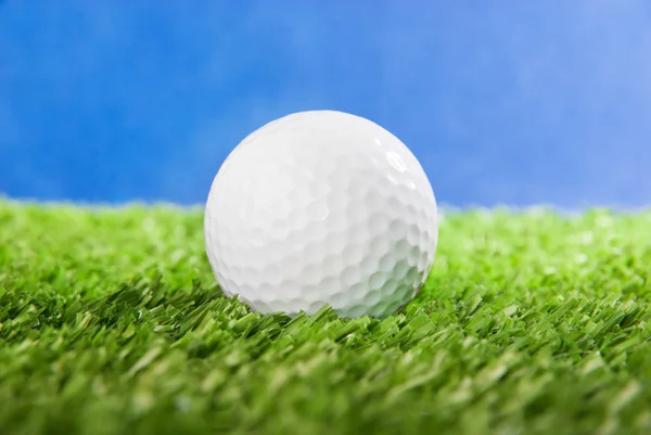 М'яч для гольфу на зеленій траві на фоні блакитного неба — стокове фото