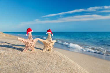 Deniz yıldızı çift Sahilde yürüyüş santa şapkalar. tatil kavramı