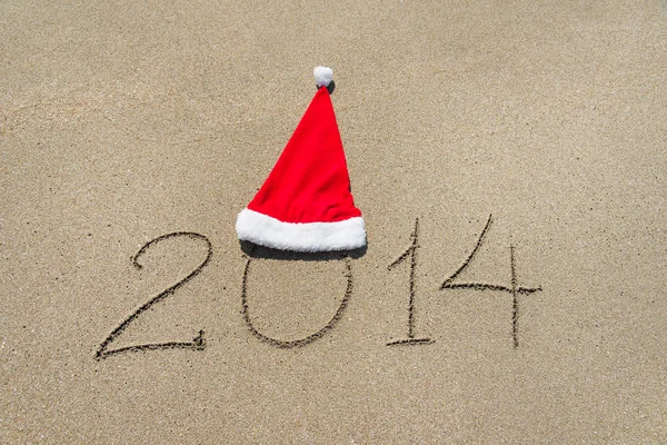 Feliz año nuevo 2014 con sombrero de Navidad en la playa de arena - vacaciones —  Fotos de Stock