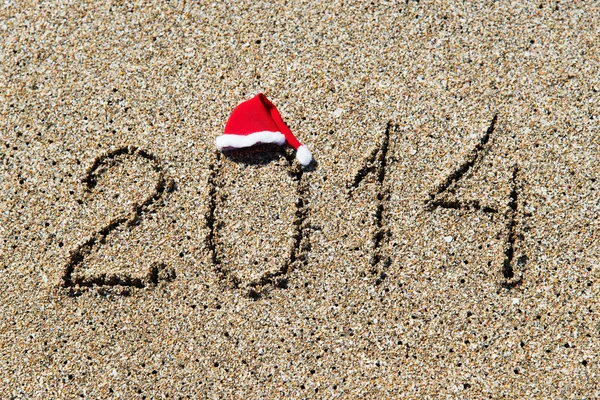 Feliz año nuevo 2014 con sombrero de Navidad en la playa de arena - vacaciones —  Fotos de Stock