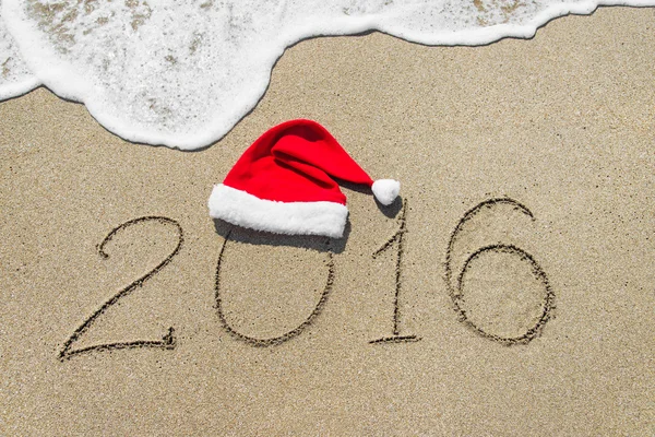 Feliz ano novo 2016 com chapéu de Natal na praia de areia — Fotografia de Stock