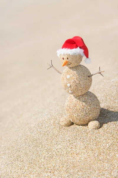 Um boneco de neve de areia sorridente no chapéu do Pai Natal. Conceito de férias de Ano Novo — Fotografia de Stock