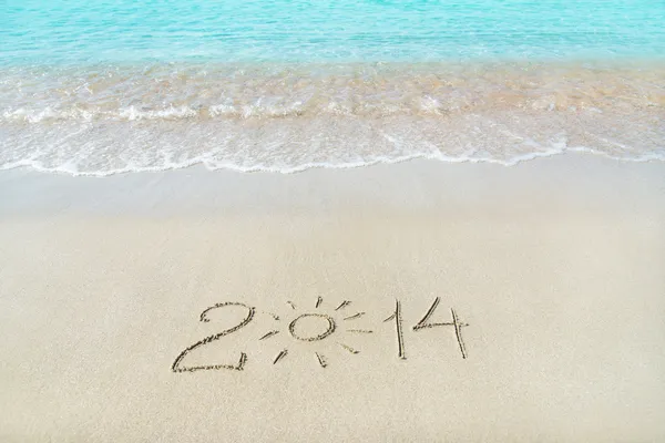 Inscription 2014 on sea sand beach with the sun rays — Stock Photo, Image