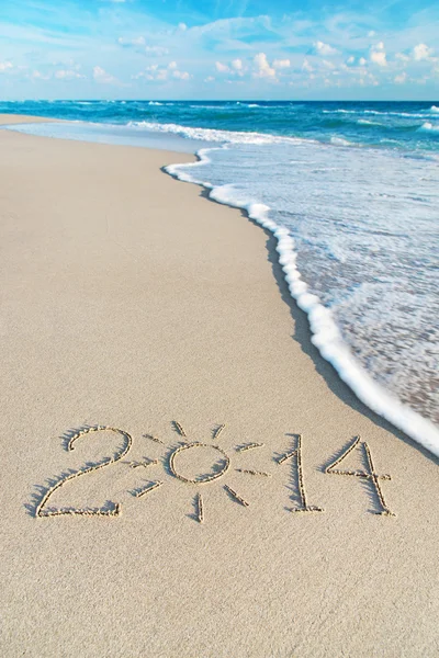 Inscription 2014 on sea sand beach with the sun rays — Stock Photo, Image