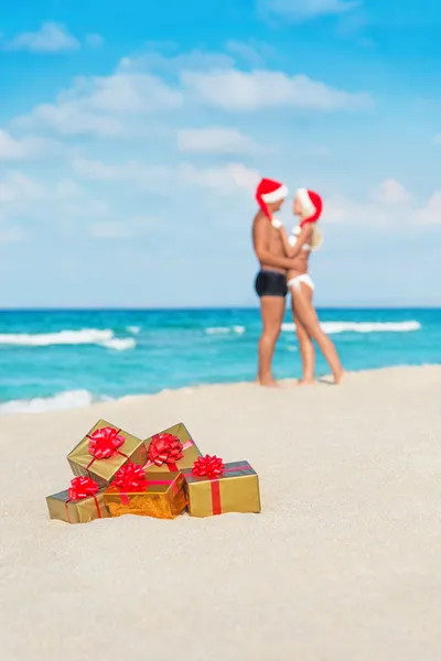 Kissing couple in santa hats at sea beach — Stock Photo, Image