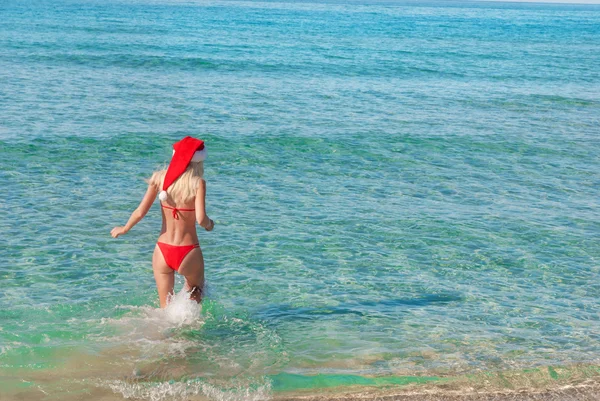 美丽的金发女人，红色的圣诞帽，在海滩上. — 图库照片