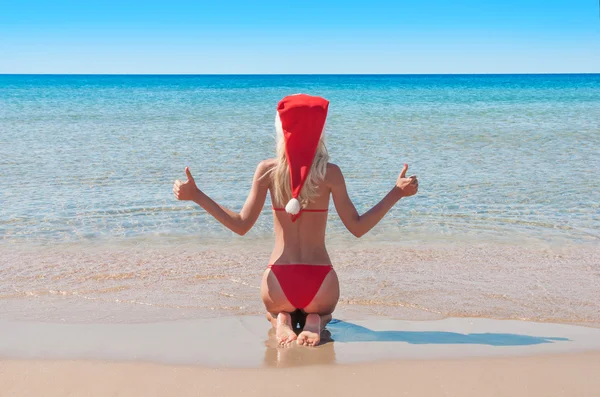 Piękne blond kobieta w czerwonym kapeluszu Boże Narodzenie na plaży. — Zdjęcie stockowe