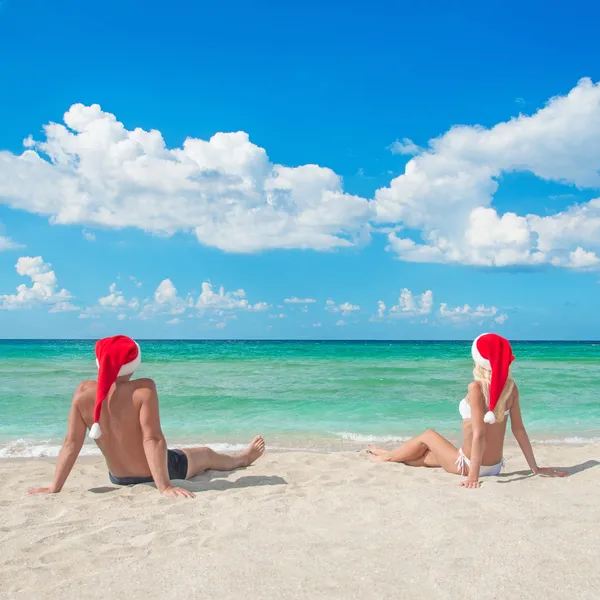 Lovers couple in santa hats at tropical sandy beach — Stock Photo, Image