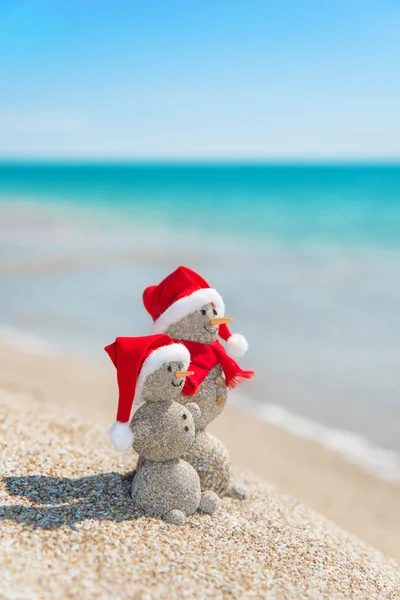 Snowmans couple at sea beach in christmas hat. — Stock Photo, Image