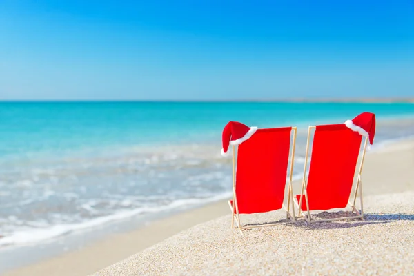 Sombrero de Santa en chaise longues en la playa de arena blanca contra el mar —  Fotos de Stock