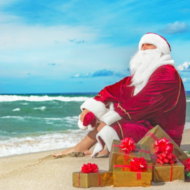 Santa Claus with many golden gifts relaxing at beach clipart