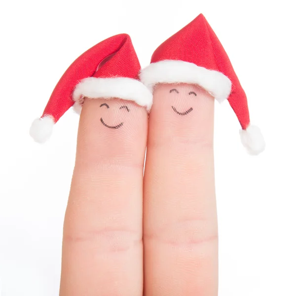 Las caras de los dedos en los sombreros de Santa. Pareja feliz celebrando concepto fo —  Fotos de Stock