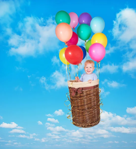 Enfant d'un an volant dans le ciel en panier avec des ballons varicolores — Photo