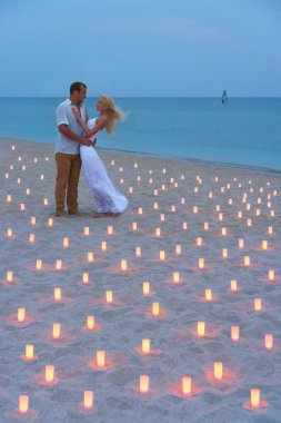 Proposal at sea beach in candles against sunset clipart