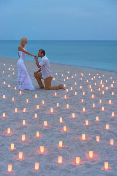 Proposition à la plage en mer aux bougies contre le coucher du soleil — Photo
