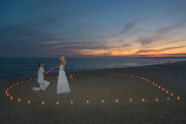 Couple in candles heart at sea beach sunset — Stock Photo, Image
