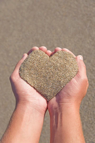 Hände, die einen Sand in Herzform halten — Stockfoto