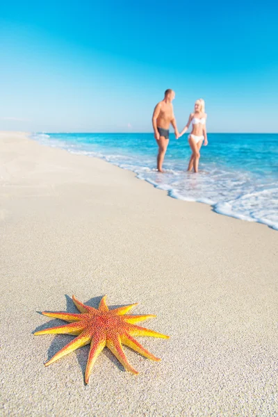 Los amantes de la pareja en la playa de arena de mar con estrellas de mar rojas — Foto de Stock