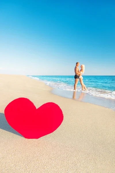 Pareja en la playa del mar y gran corazón rojo —  Fotos de Stock