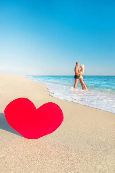 Pareja en la playa del mar y gran corazón rojo —  Fotos de Stock