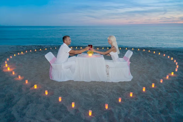 Pareja en la playa cena romántica con velas corazón —  Fotos de Stock